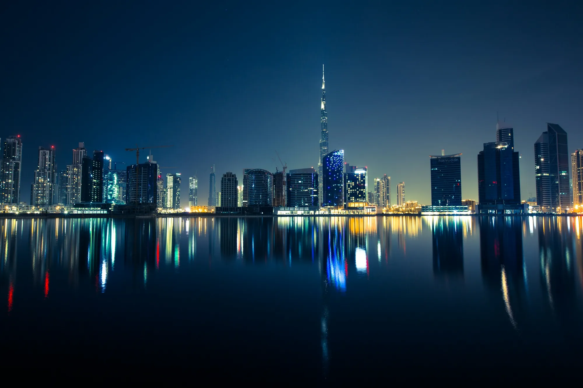 The Dubai skyline at night, mirrored in the water